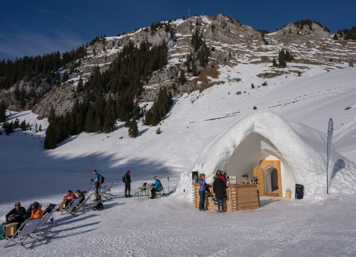 Snow domes of an alpine igloo village standing on a mountain terrace in the Bernese Oberland.