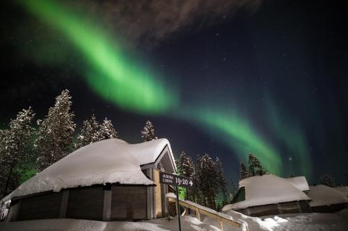 Aurora cabins spread along tracks through open snow at the edge of Lapland fell country.